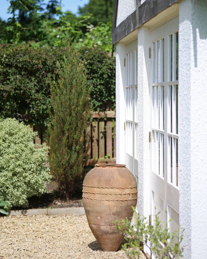 Huge antique olive pot in front of Summer house in English garden