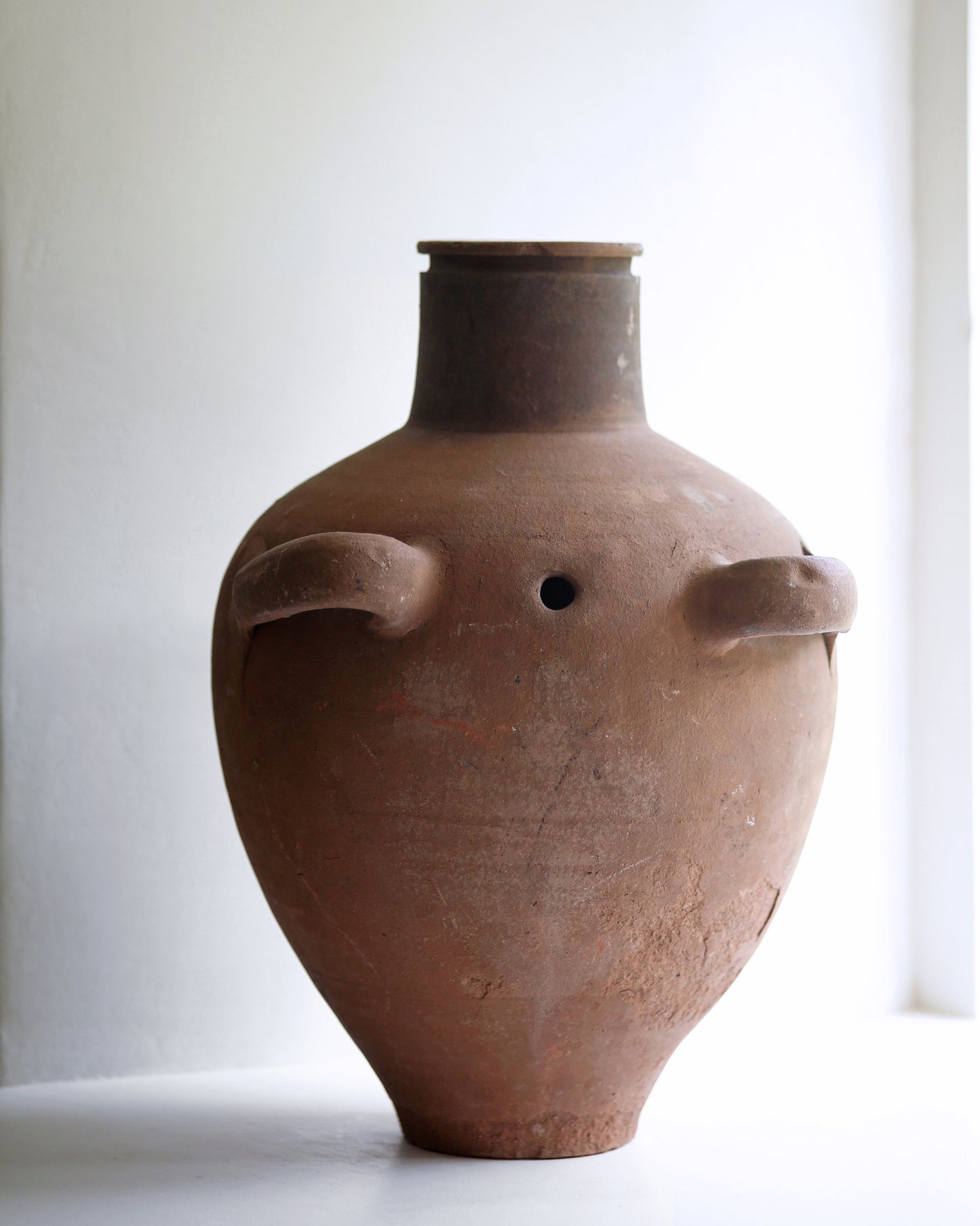 Mid brown terracotta antique amphora with two front handles and drainage hole