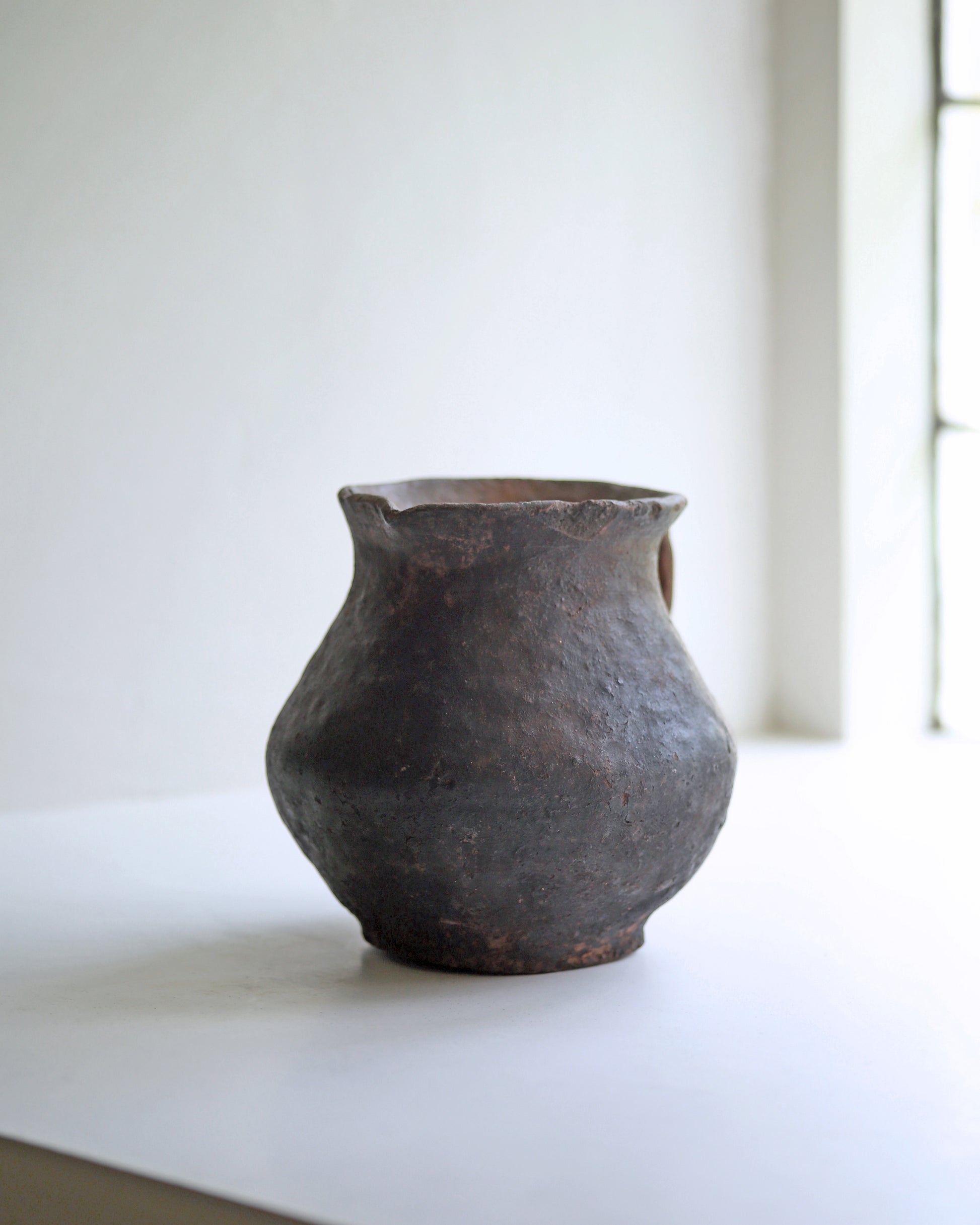 Hand thrown organic shape rustic clay jug in dark baked terracotta