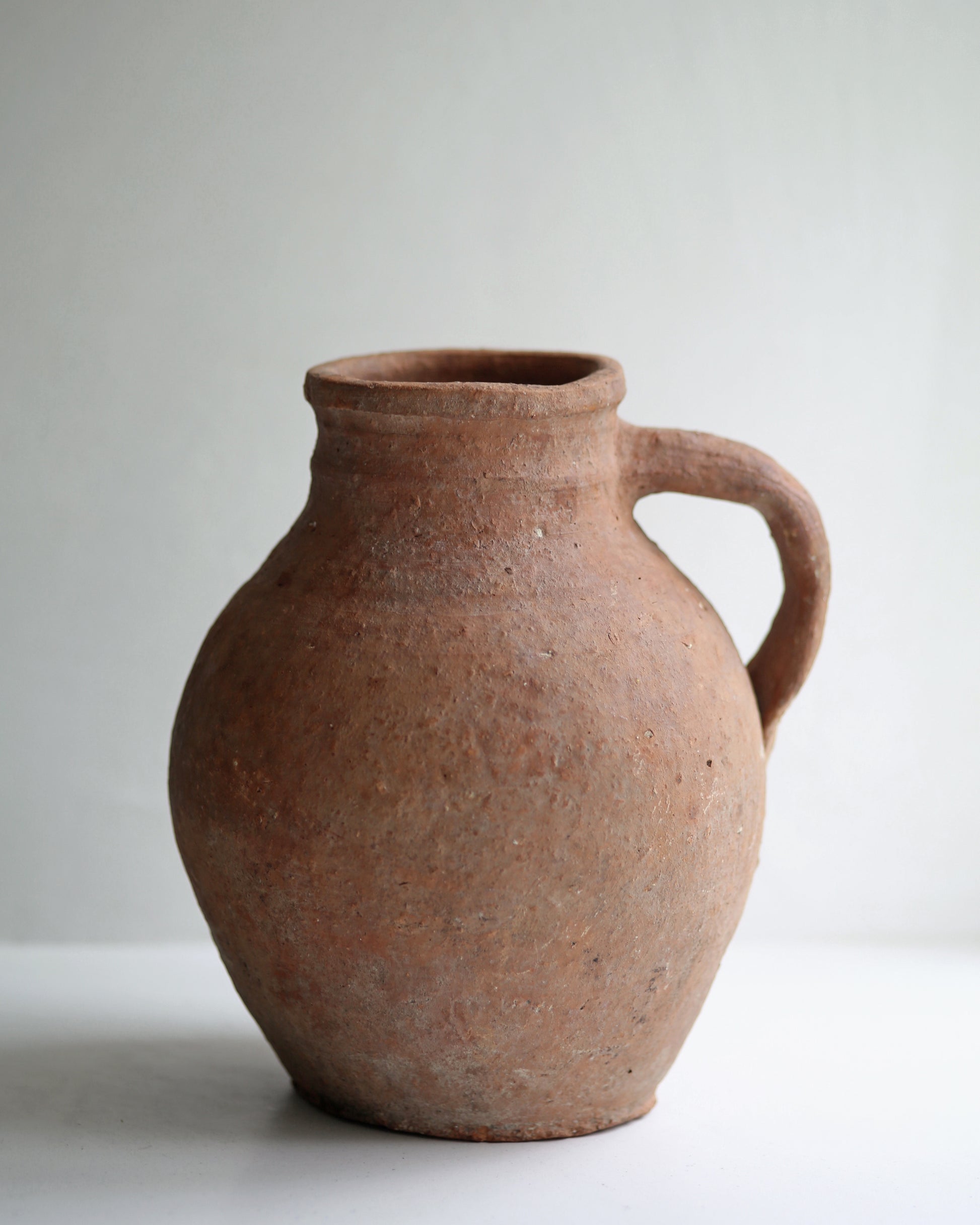 Aged patina and artisan made character of sweet terracotta pitcher pot