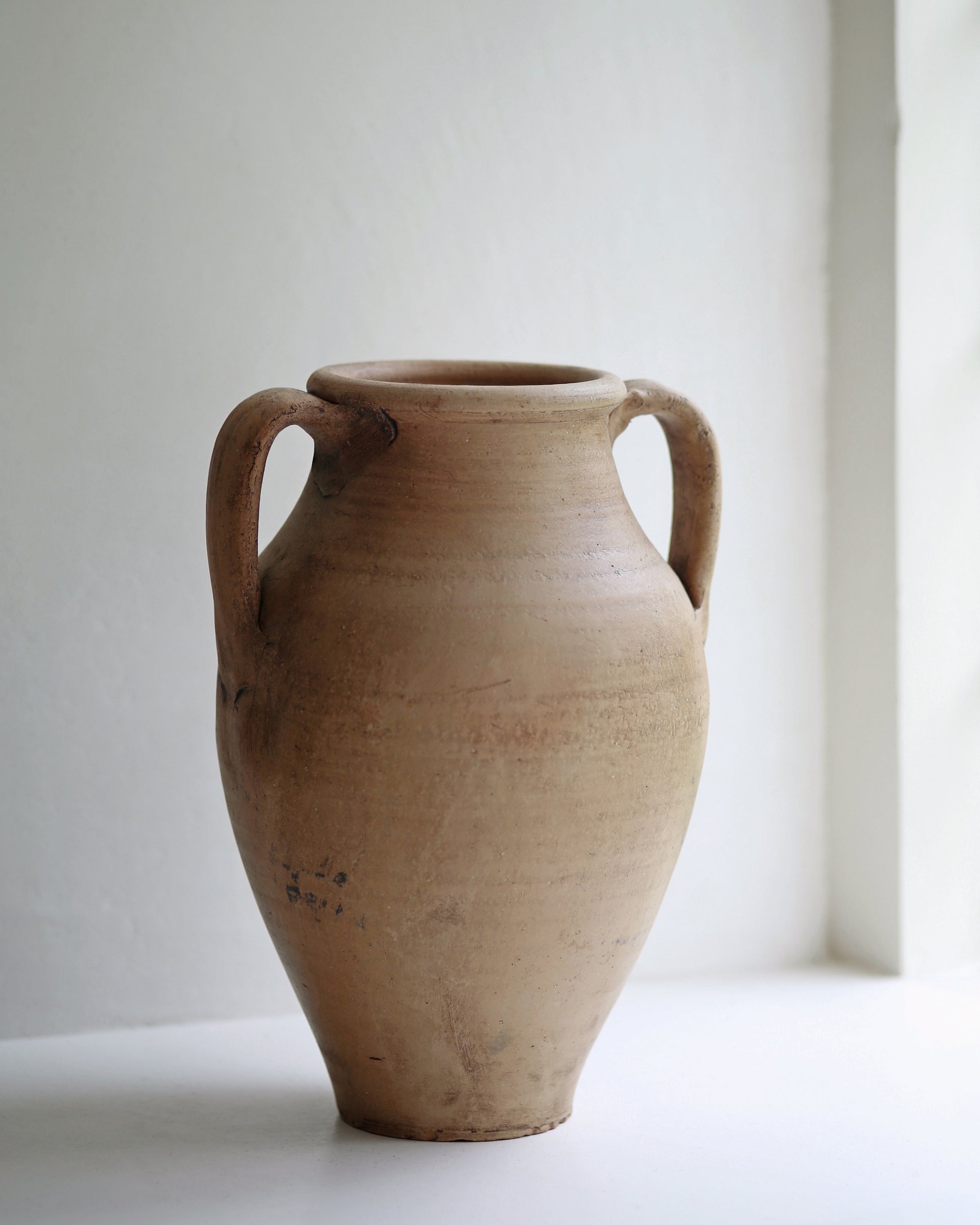 Pale terracotta pot stood in window sill