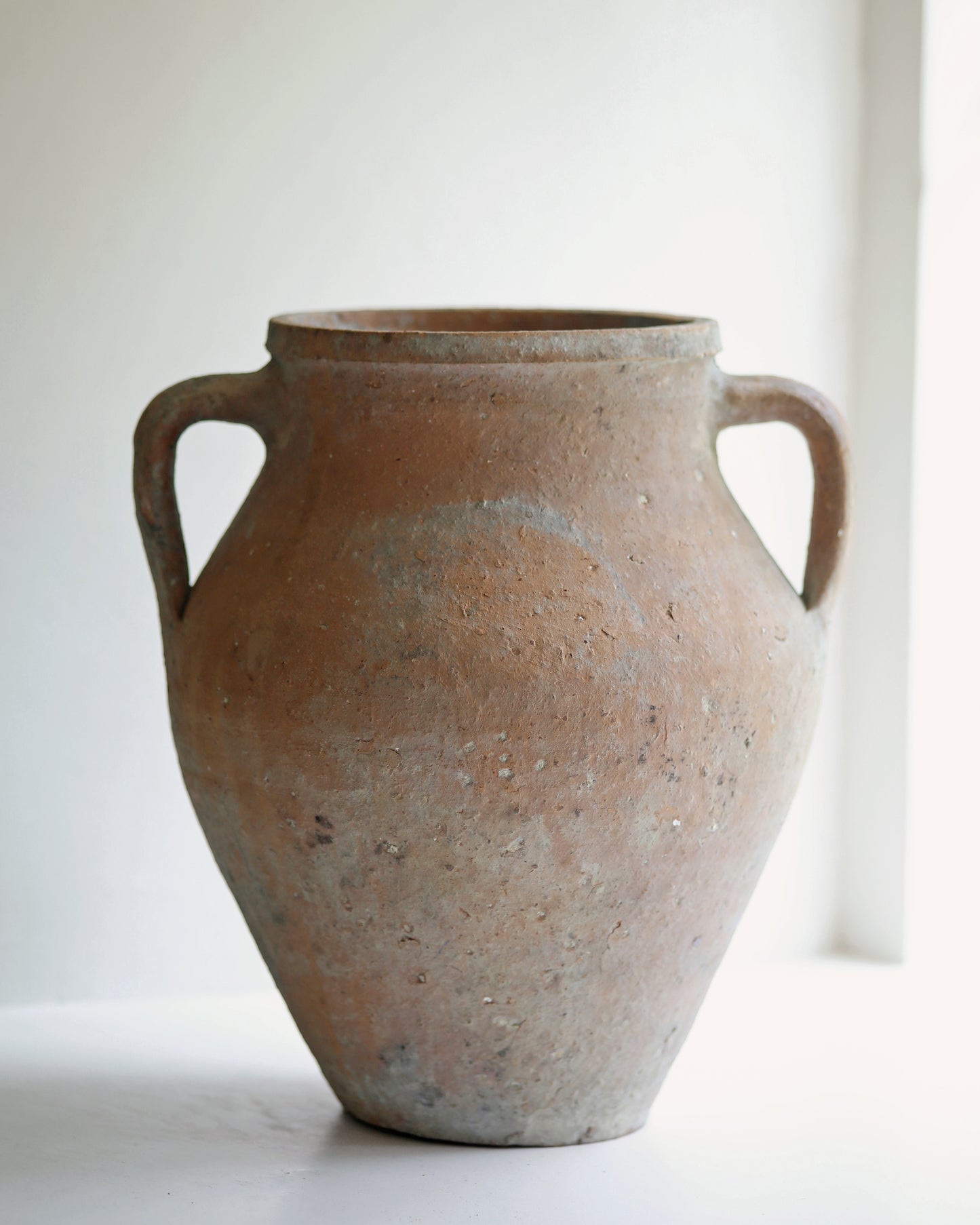 Aged patina finish of rustic textured pottery for the home displayed in sunny window sill