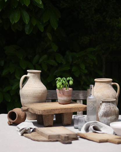 Antique mediterranean olive pots and rustic bread boards for decorative al fresco dining setup