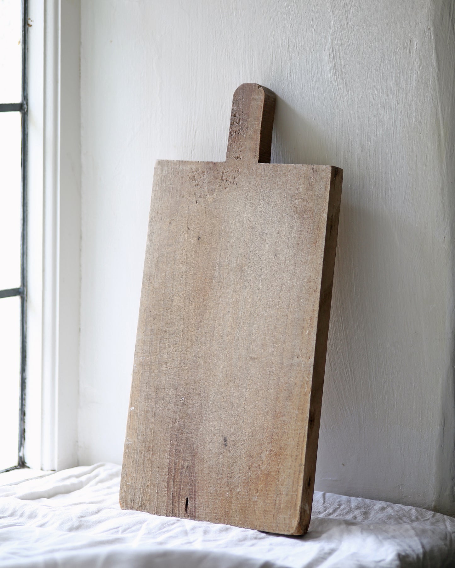 Pale wood rustic chopping board in kitchen on table cloth