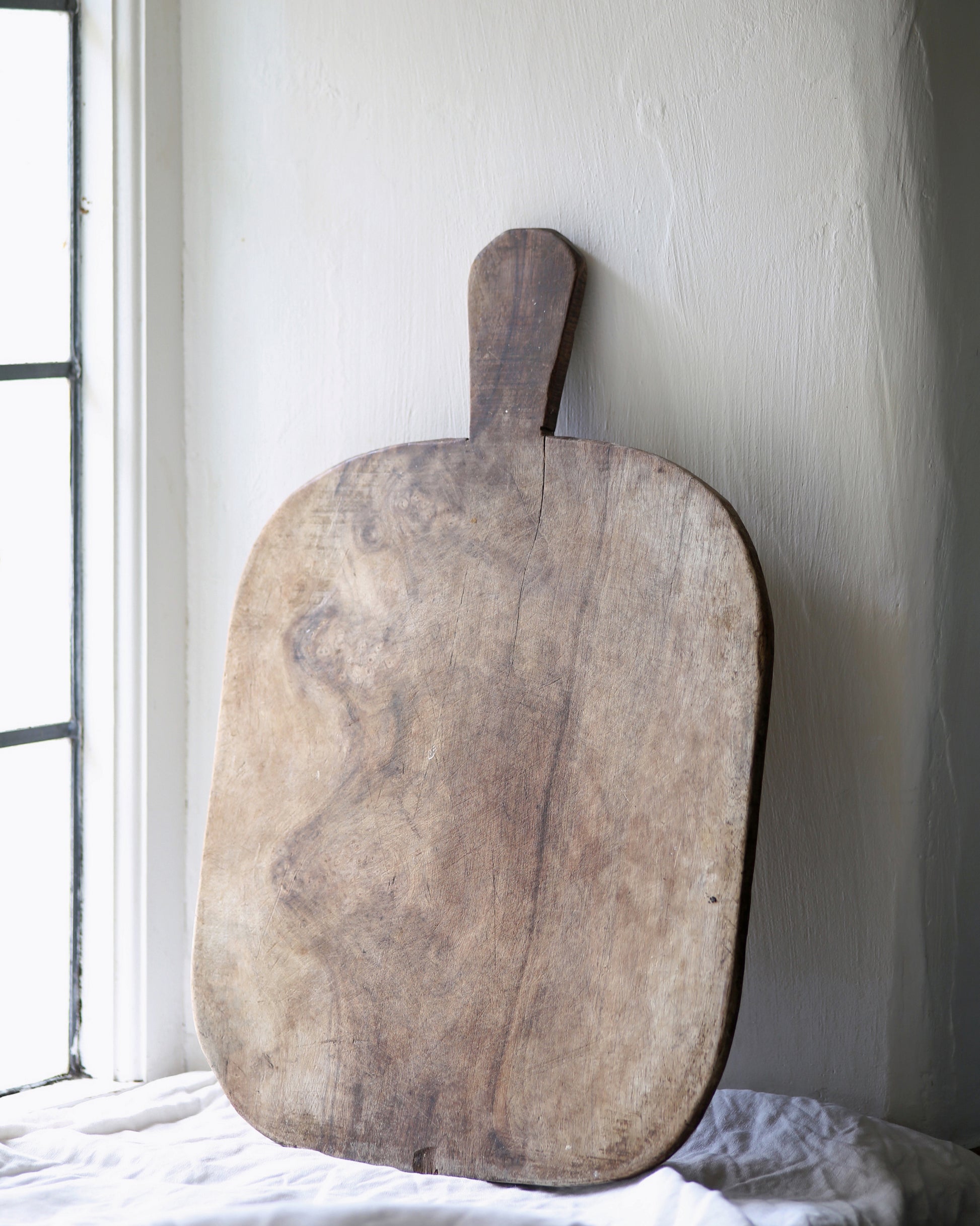 Unique vintage rustic wooden bread board in kitchen window