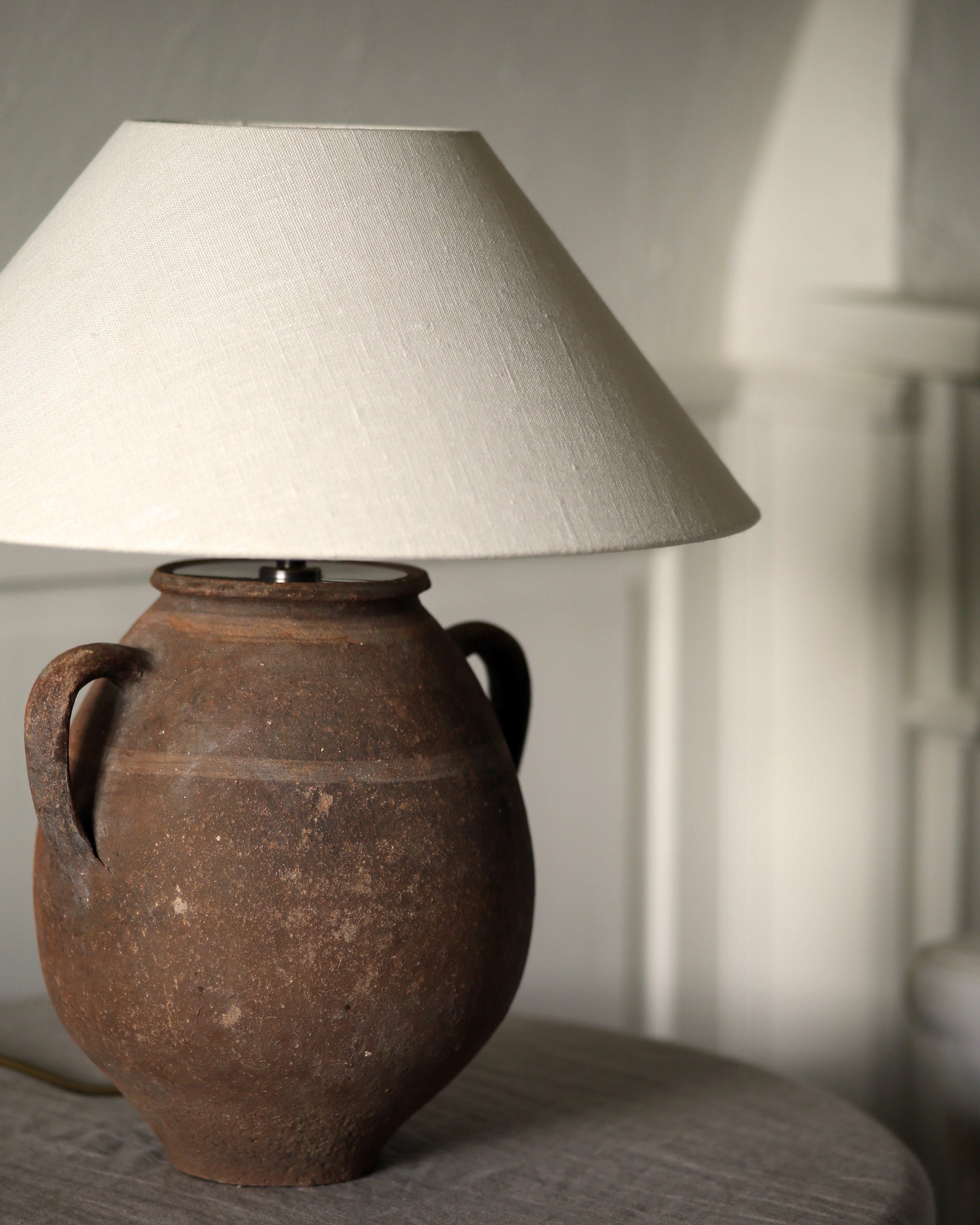 Rustic textured surface of olive pot and linen textured lampshade